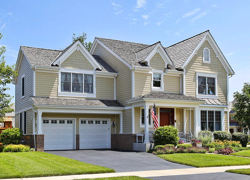 Large American Yellow House with Two Car Garage, Driveway, and Green Grass Front Yard